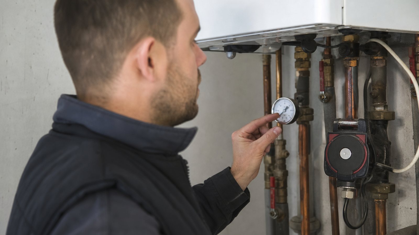 Chauffagiste cochant une grille de contrôle sur tablette devant une chaudière au gaz
